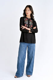 indigrey Aurora black shirt featuring handcrafted floral cross stitch embroidery worn with blue wide-leg jeans