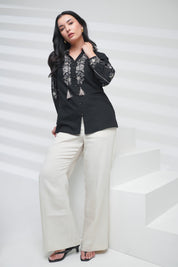 indigrey black shirt with floral embroidery on neckline and sleeves, worn by a woman with white trousers