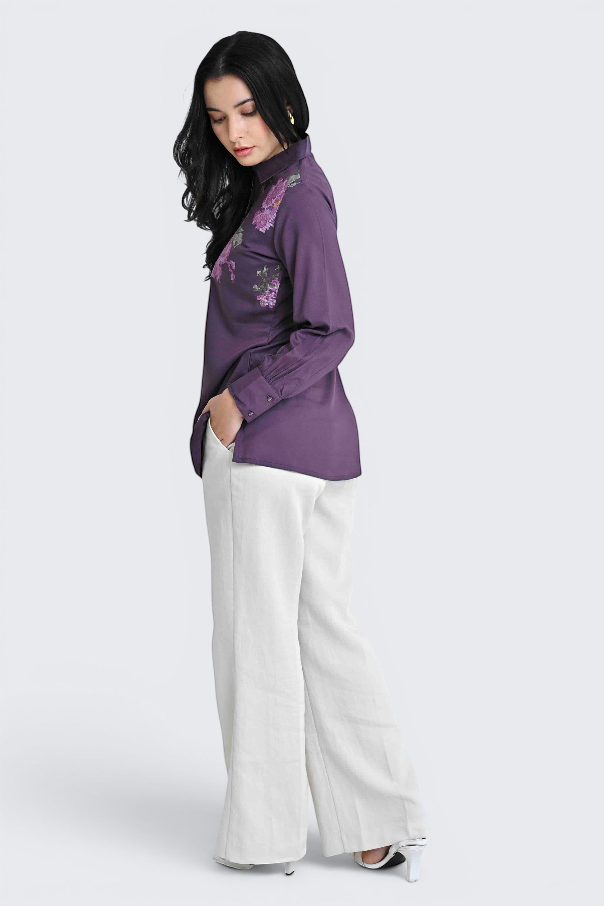 indigrey Ambrosia purple shirt featuring pixel cross stitch floral embroidery worn by a model with white trousers