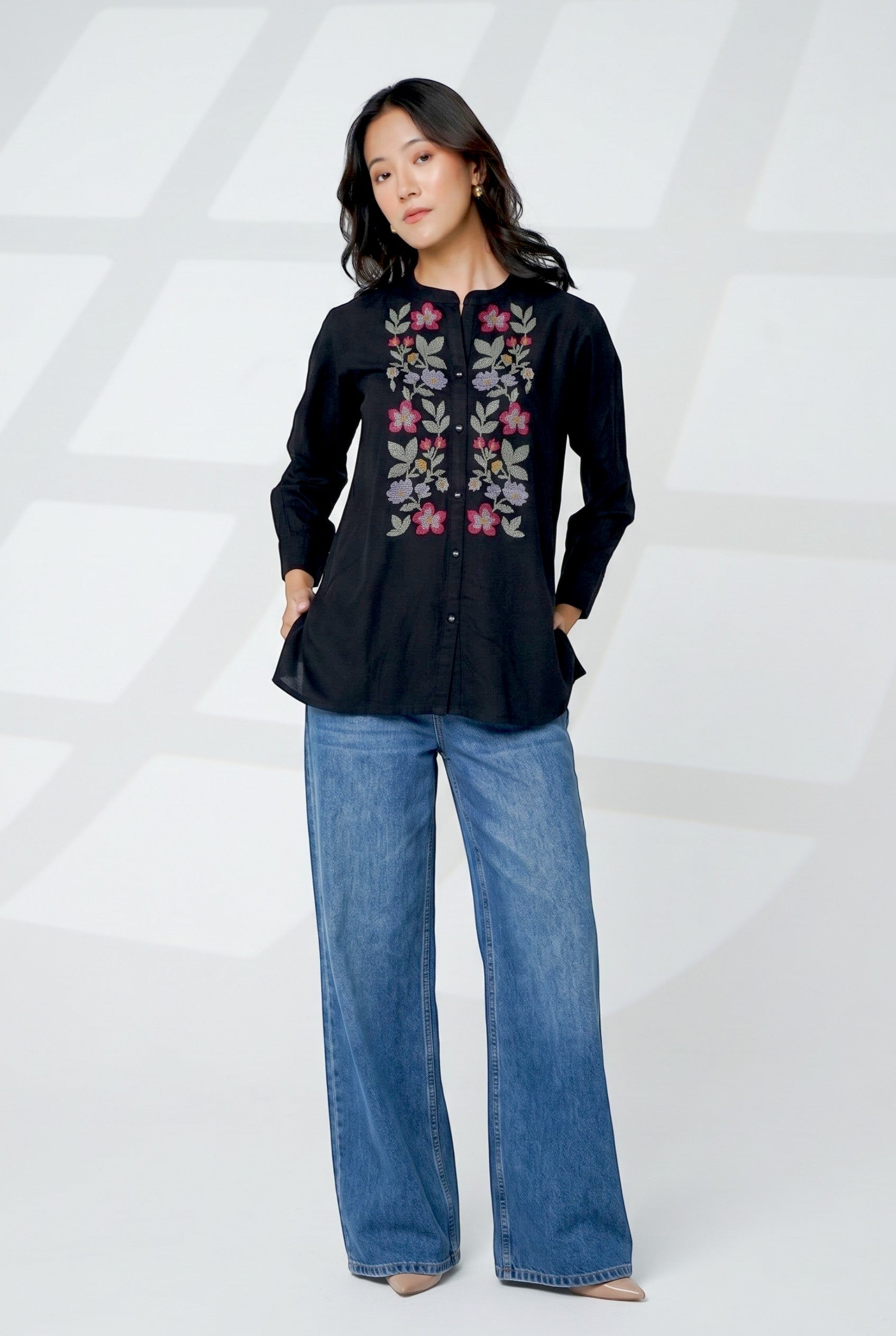 indigrey Aurora black shirt featuring handcrafted floral cross stitch embroidery, worn with blue wide-leg jeans