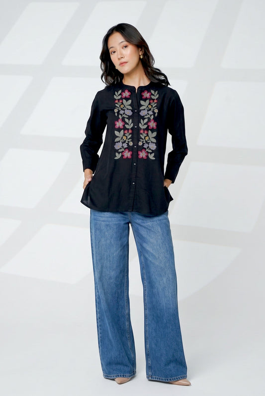 indigrey Aurora black shirt featuring handcrafted floral cross stitch embroidery, worn with blue wide-leg jeans
