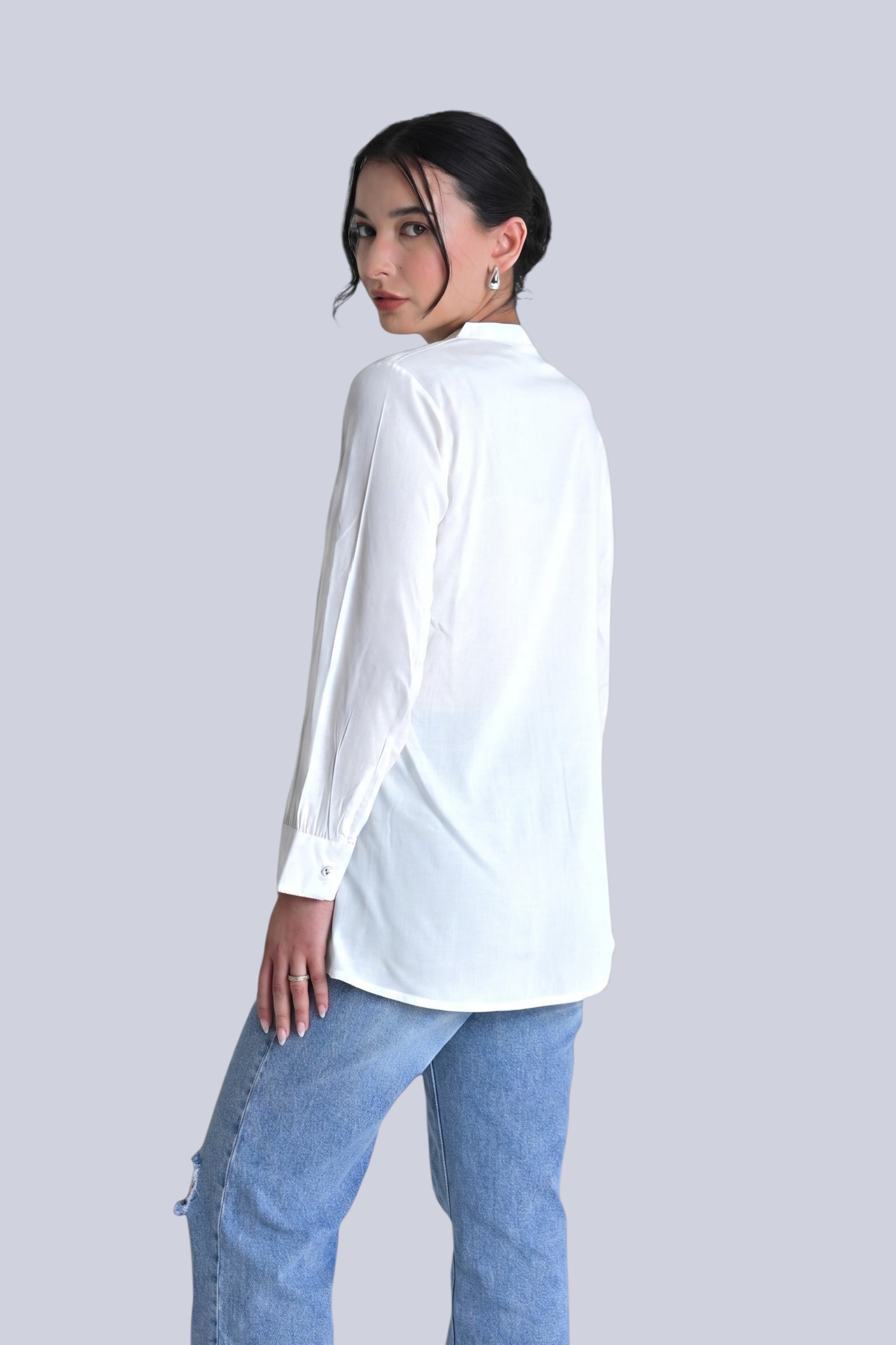 Model wearing an indigrey white Aurora shirt with floral embroidery, paired with blue jeans and silver heels.