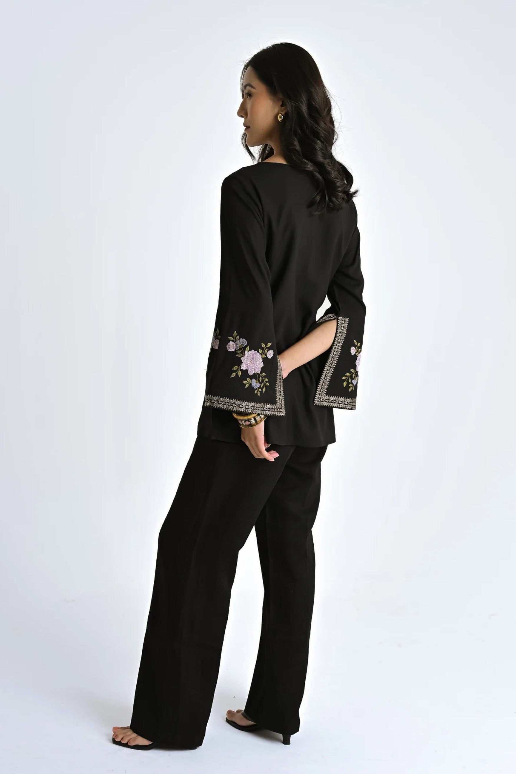 indigrey black viscose top with floral embroidery on flared bell sleeves and tassel accents worn by a model