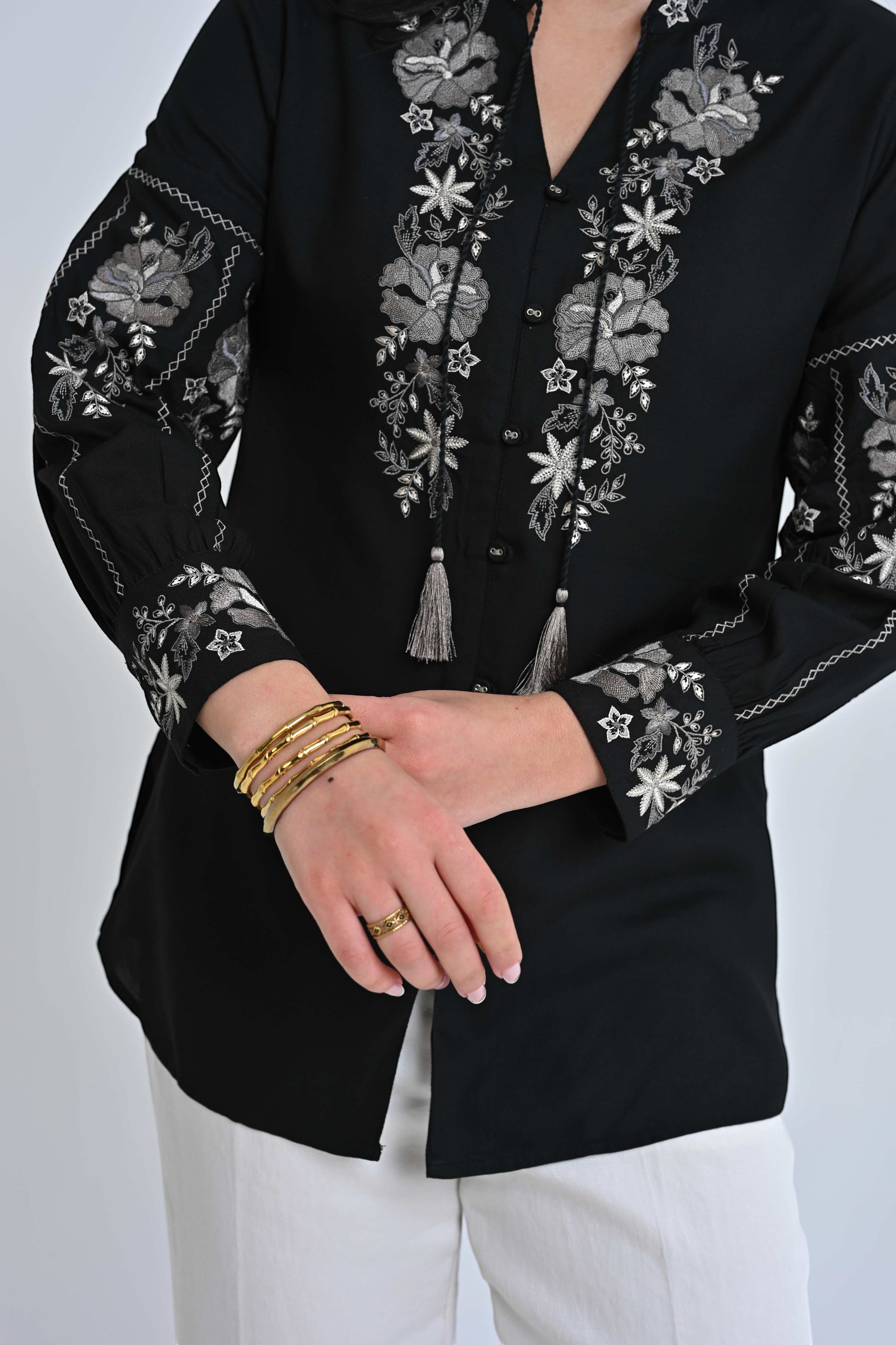 indigrey black shirt with grey floral embroidery on the neckline and sleeves featuring tassel ties and gold bangles