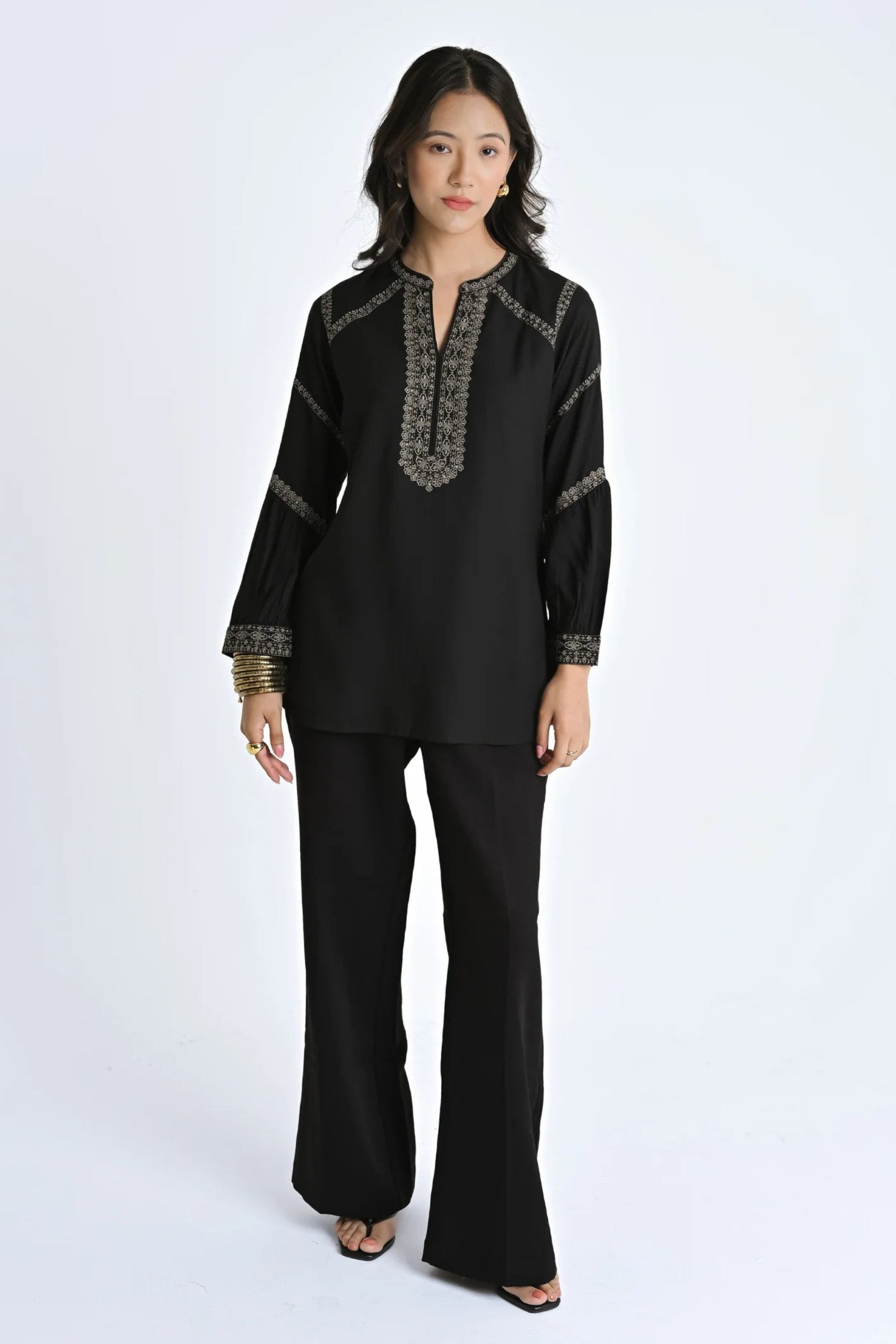 Model wearing an indigrey black June top with intricate filigree traceline floral embroidery and long sleeves.
