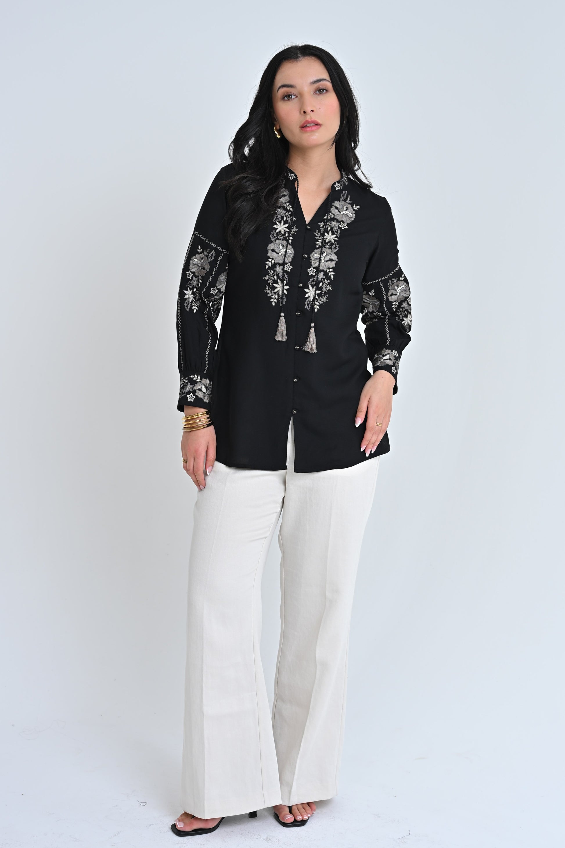 A model wearing an indigrey black shirt with intricate floral embroidery on the neckline and sleeves.