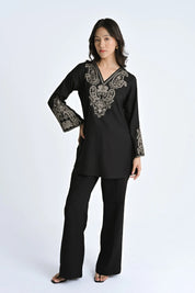 Model wearing an indigrey black V-neck top with intricate corded stem fill embroidery on the neckline and sleeves.