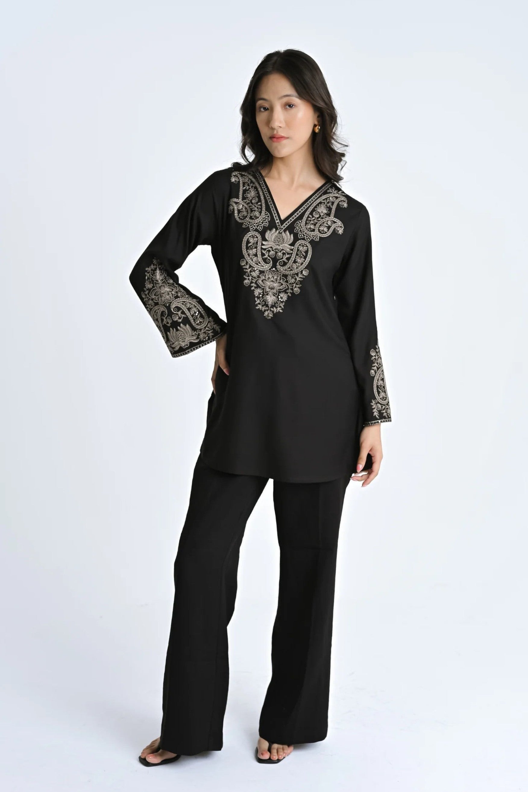 Model wearing an indigrey black V-neck top with intricate corded stem fill embroidery on the neckline and sleeves.