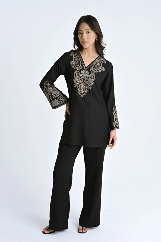 Model wearing an indigrey black V-neck top with intricate corded stem fill embroidery on the neckline and sleeves.
