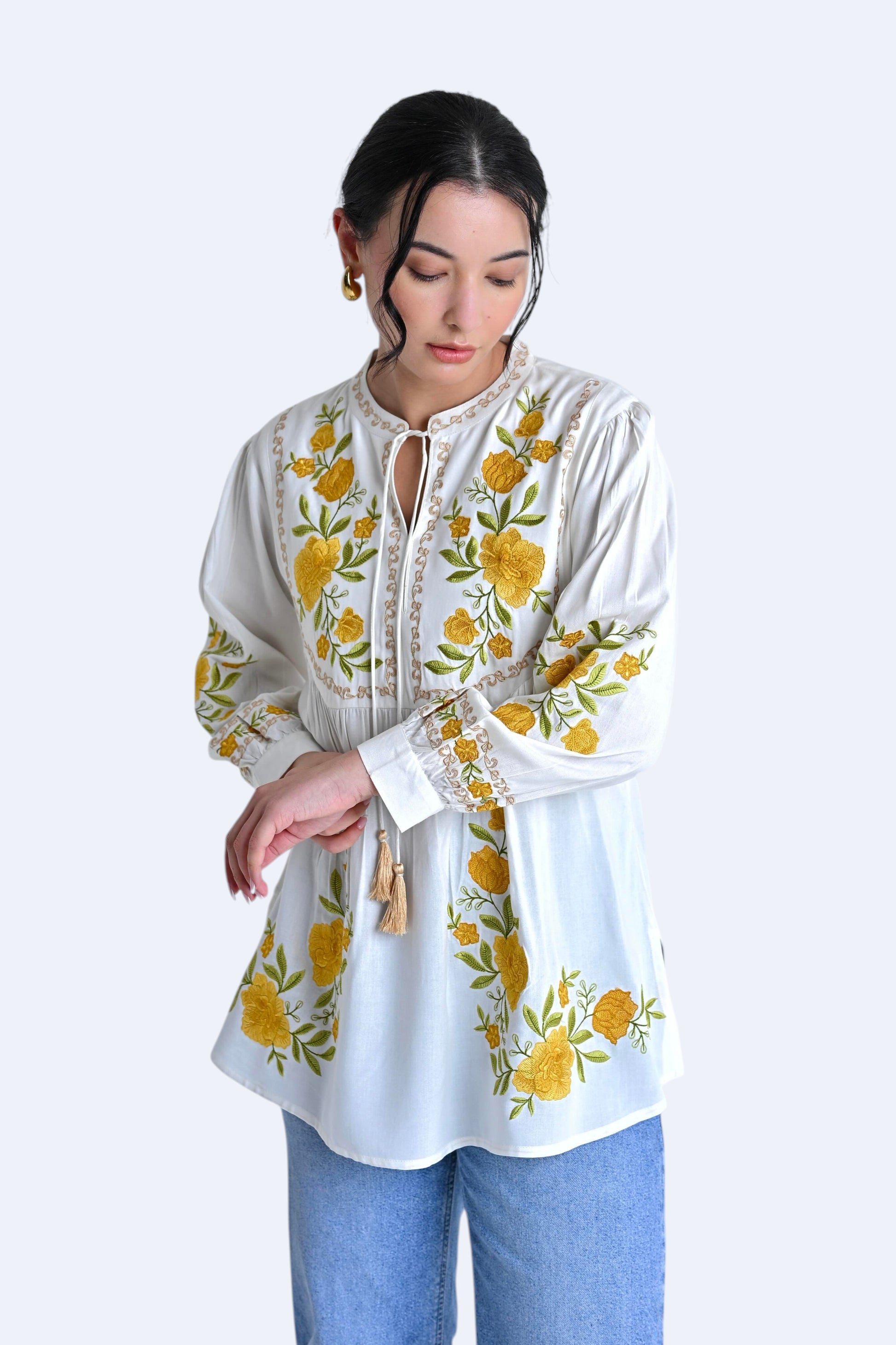 indigrey Goa white top with yellow floral Tatami gradient embroidery on yoke and sleeves, worn by a woman.