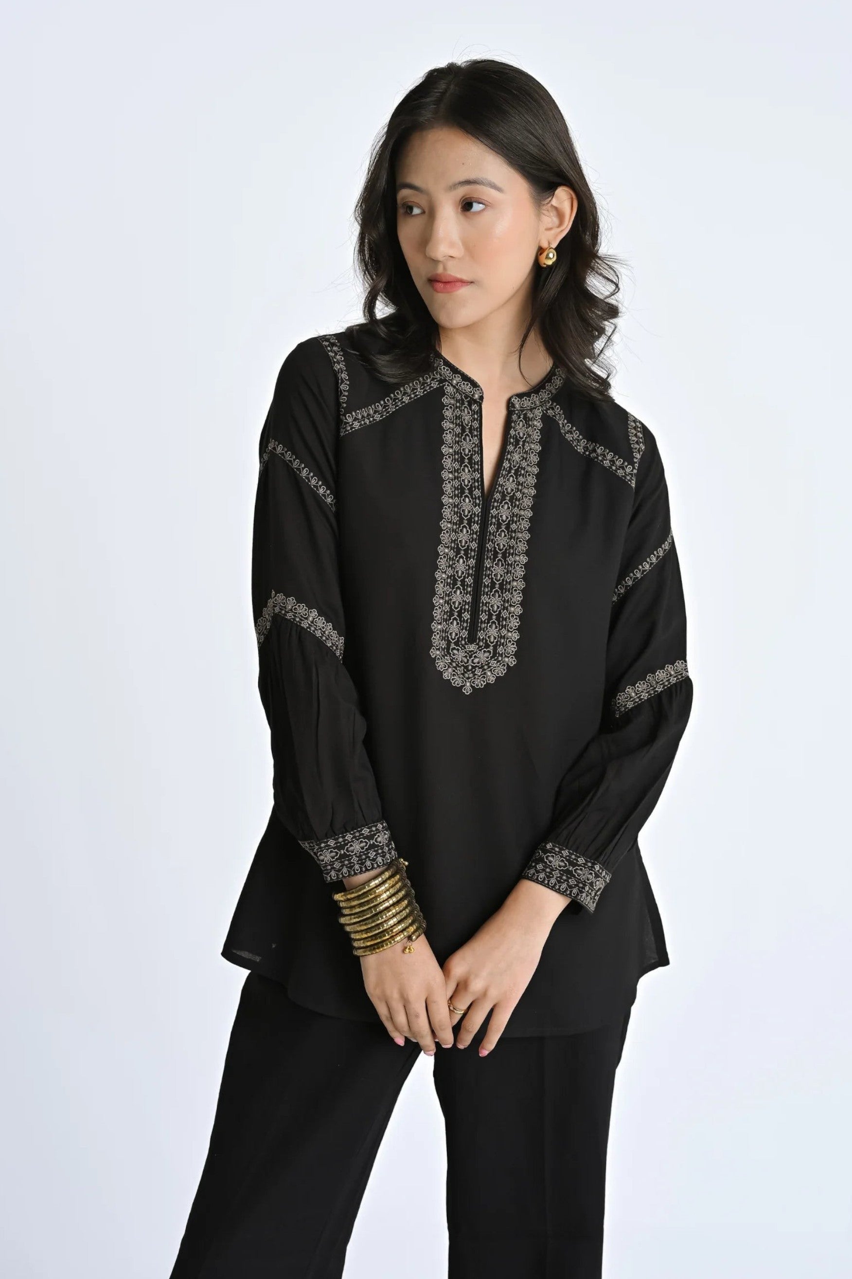 indigrey June black top with intricate filigree traceline floral embroidery, long sleeves, and a split neckline.