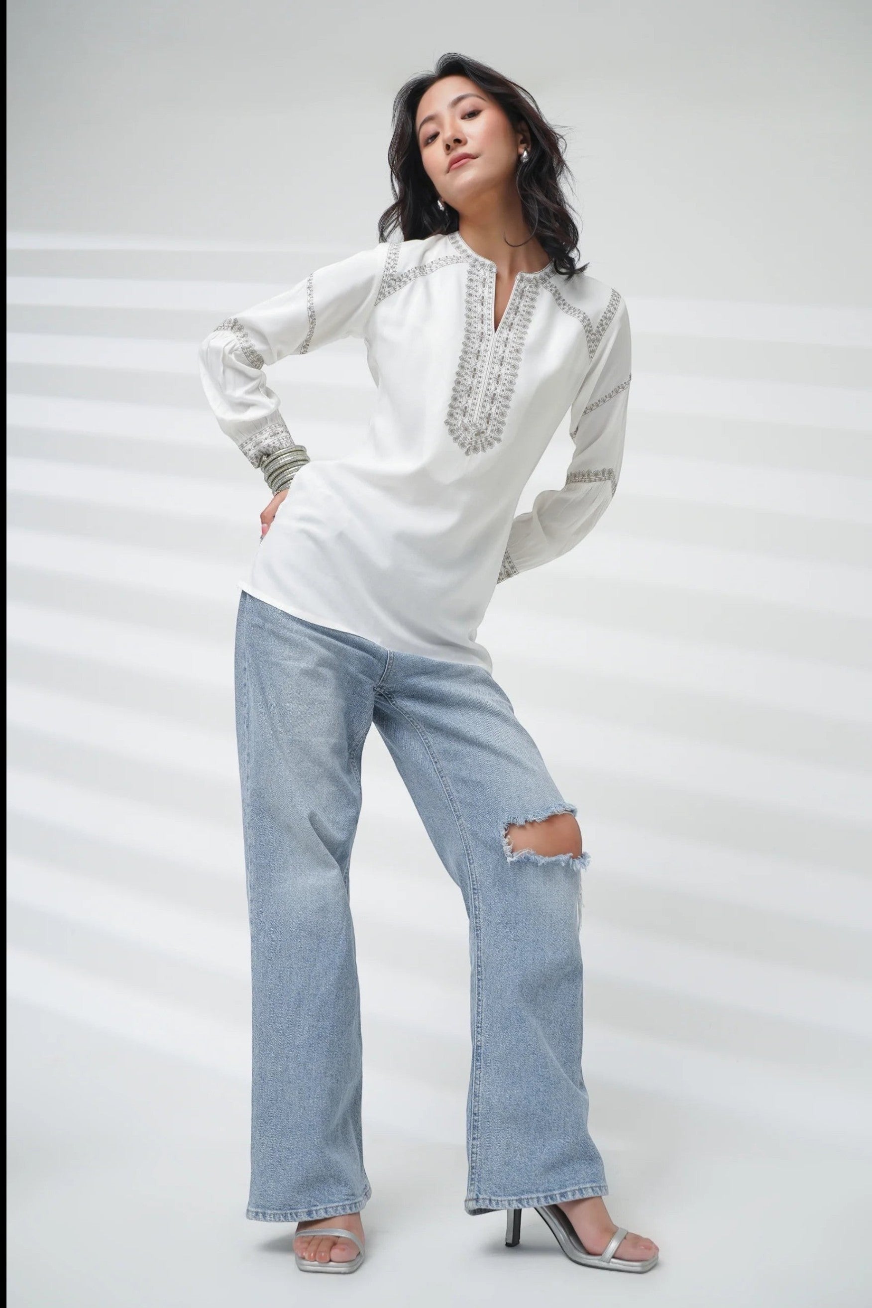Model wearing an indigrey white June top with delicate filigree traceline embroidery and a split neckline.