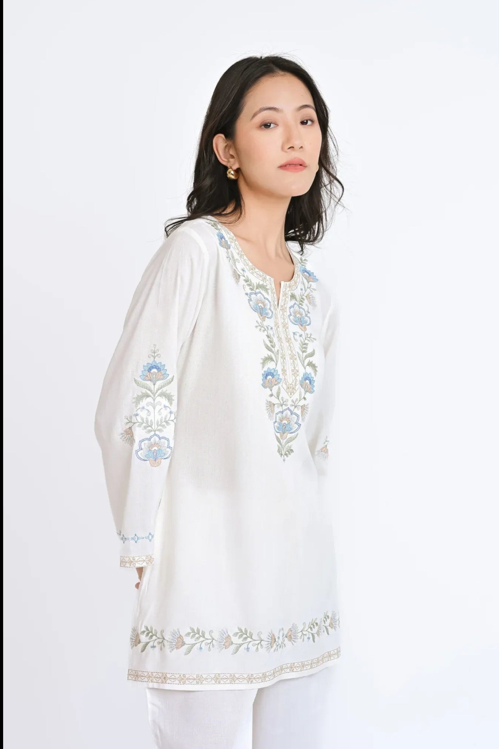 Model wearing a white indigrey Kaia co-ord set featuring delicate blue and green Kashmiri-inspired floral embroidery.