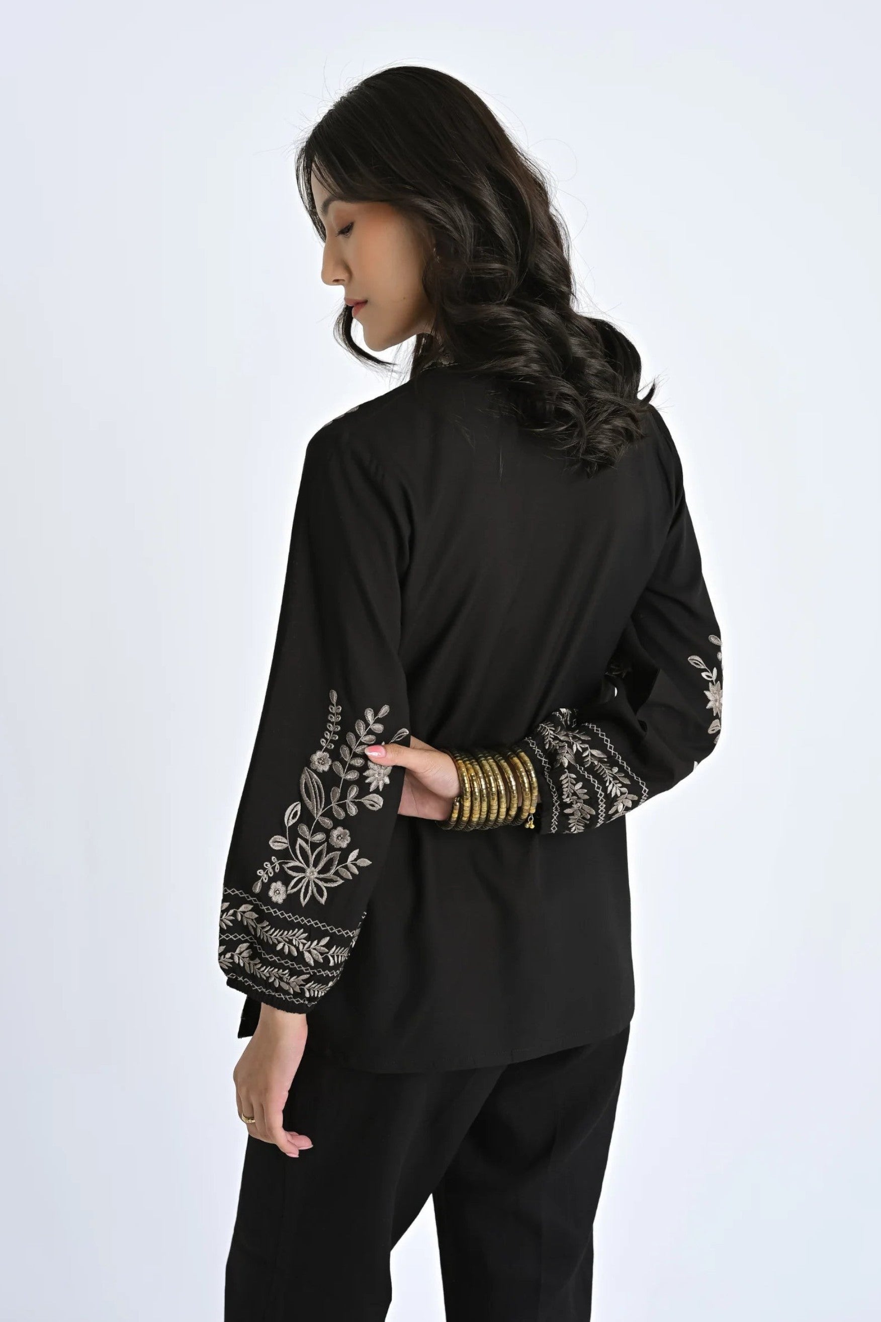 indigrey Luna black viscose shirt with intricate floral Tatami embroidery on sleeves, worn by a woman from the back.