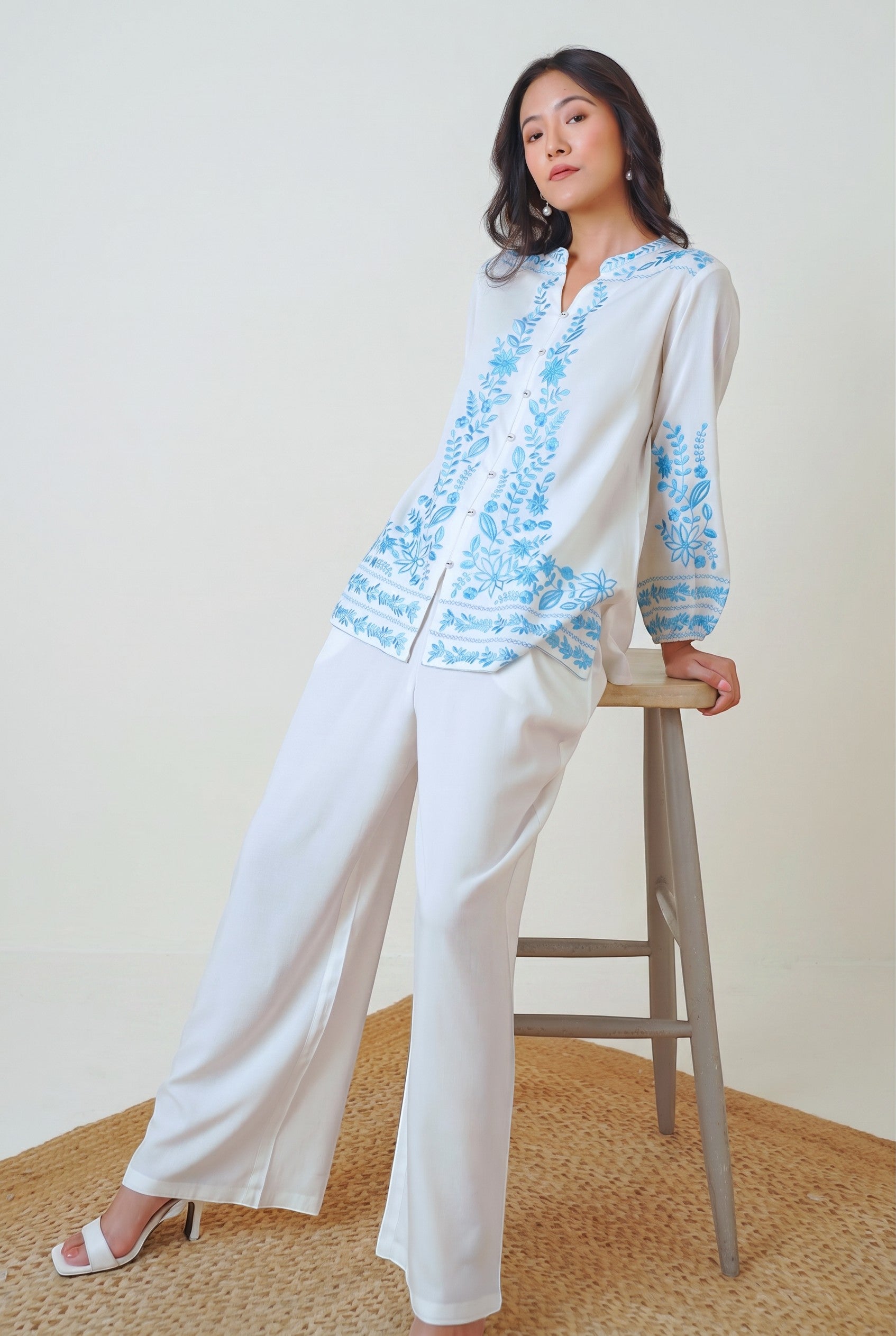 indigrey Luna white viscose shirt featuring blue floral Tatami embroidery on collar, sleeves, and hem worn by a model