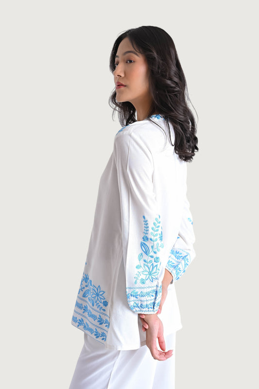 indigrey white Luna shirt in soft viscose with blue Tatami floral embroidery on sleeves and hem, side profile view.