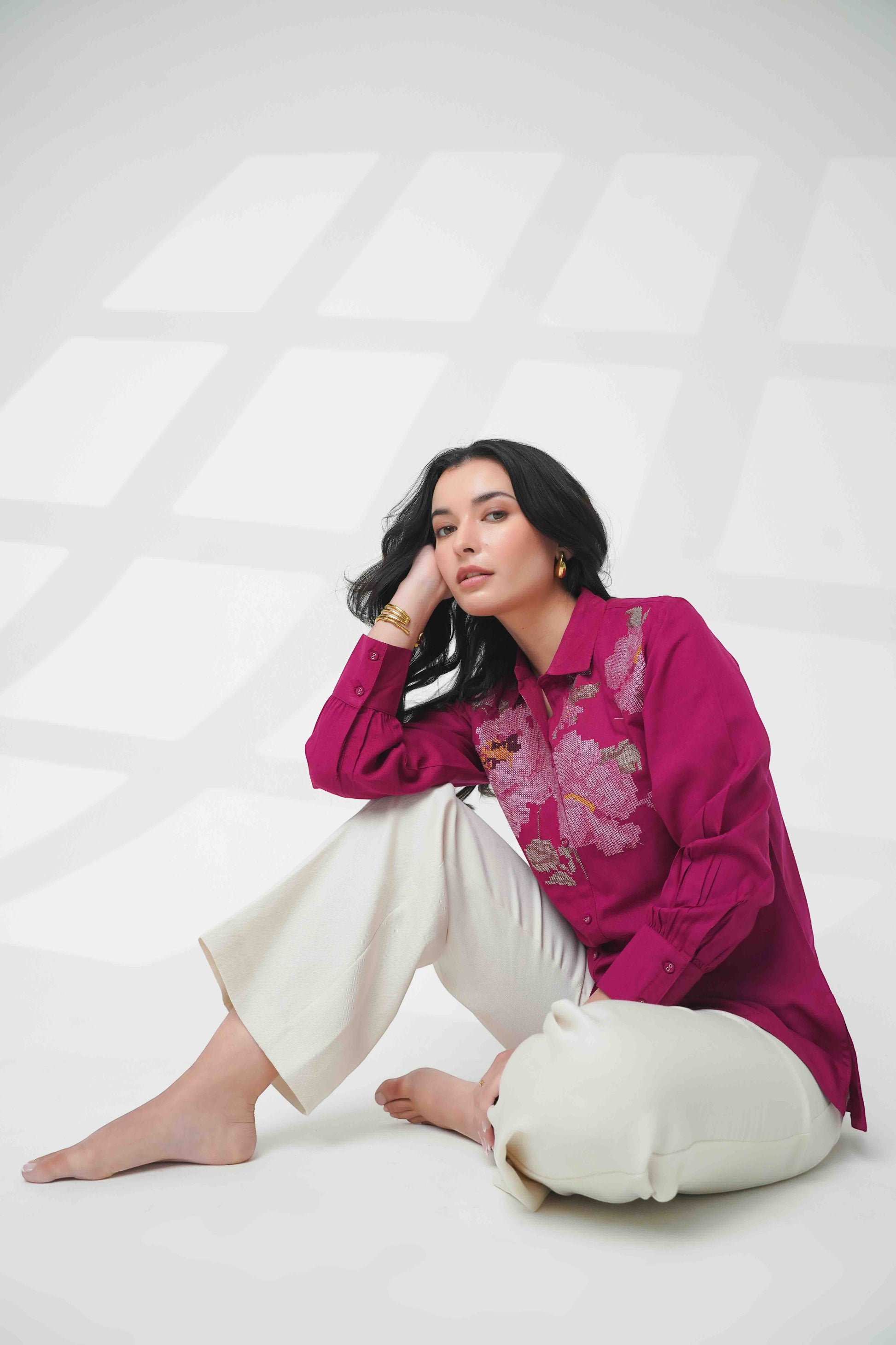 indigrey magenta long sleeve button down shirt with floral chest embroidery worn by a woman with white trousers