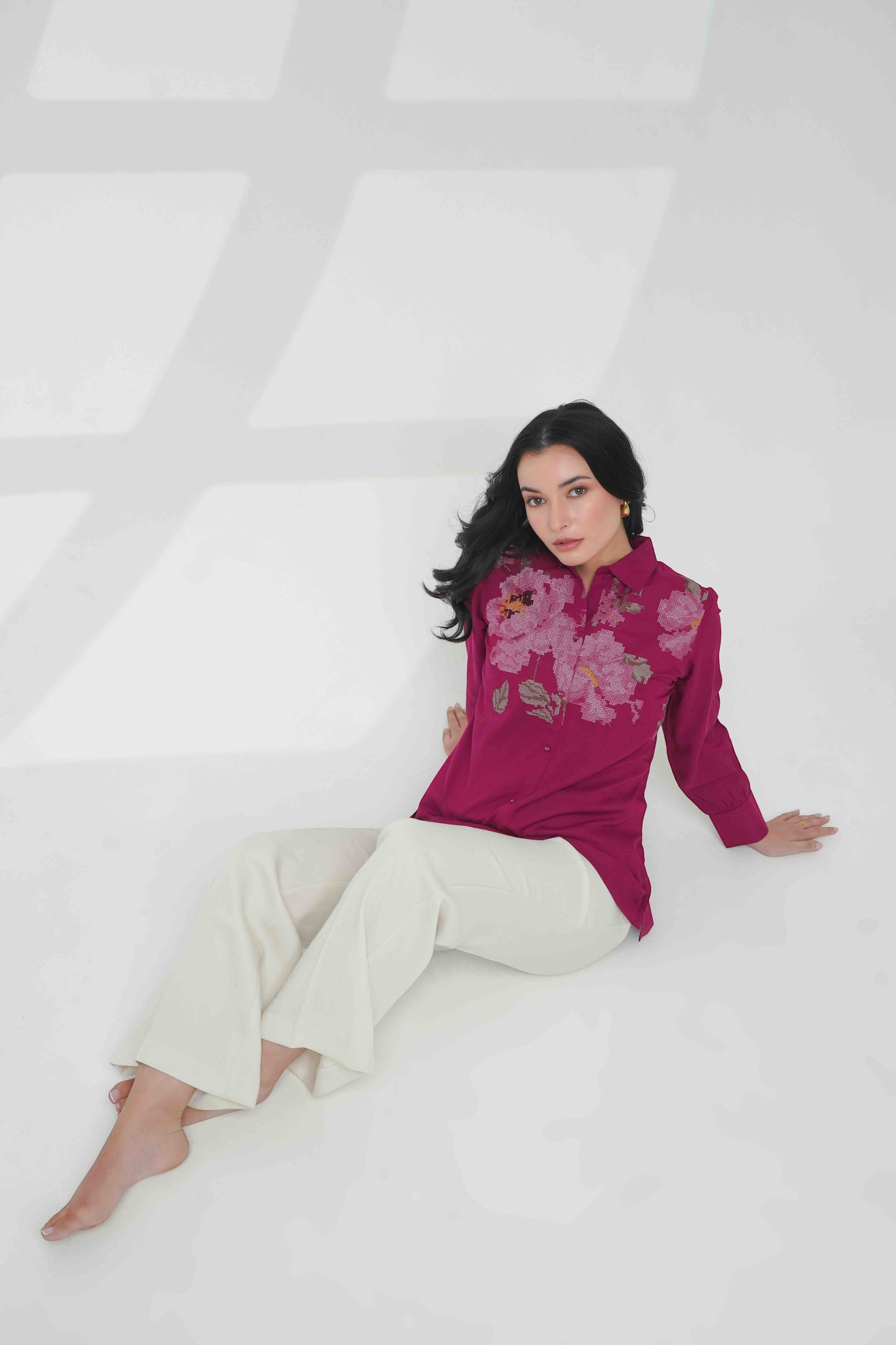 indigrey magenta long sleeve button down shirt with floral chest embroidery worn by a woman with white trousers