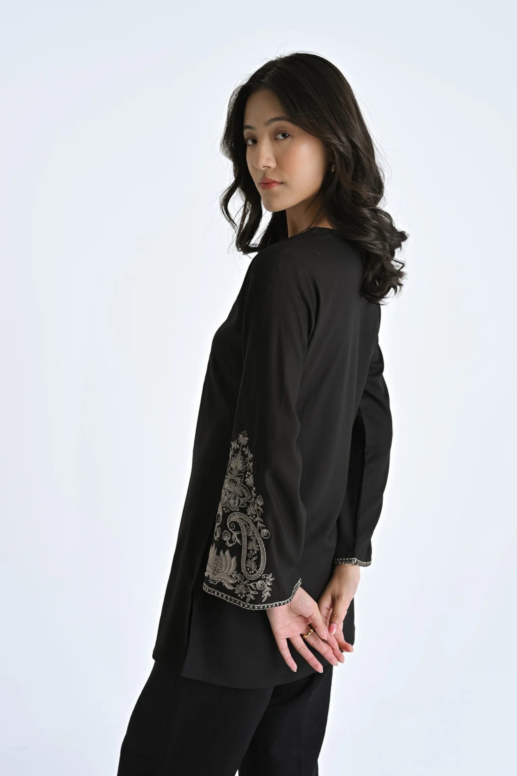 indigrey black Raya top with V-neck, flared sleeves, and intricate corded stem fill embroidery on a woman