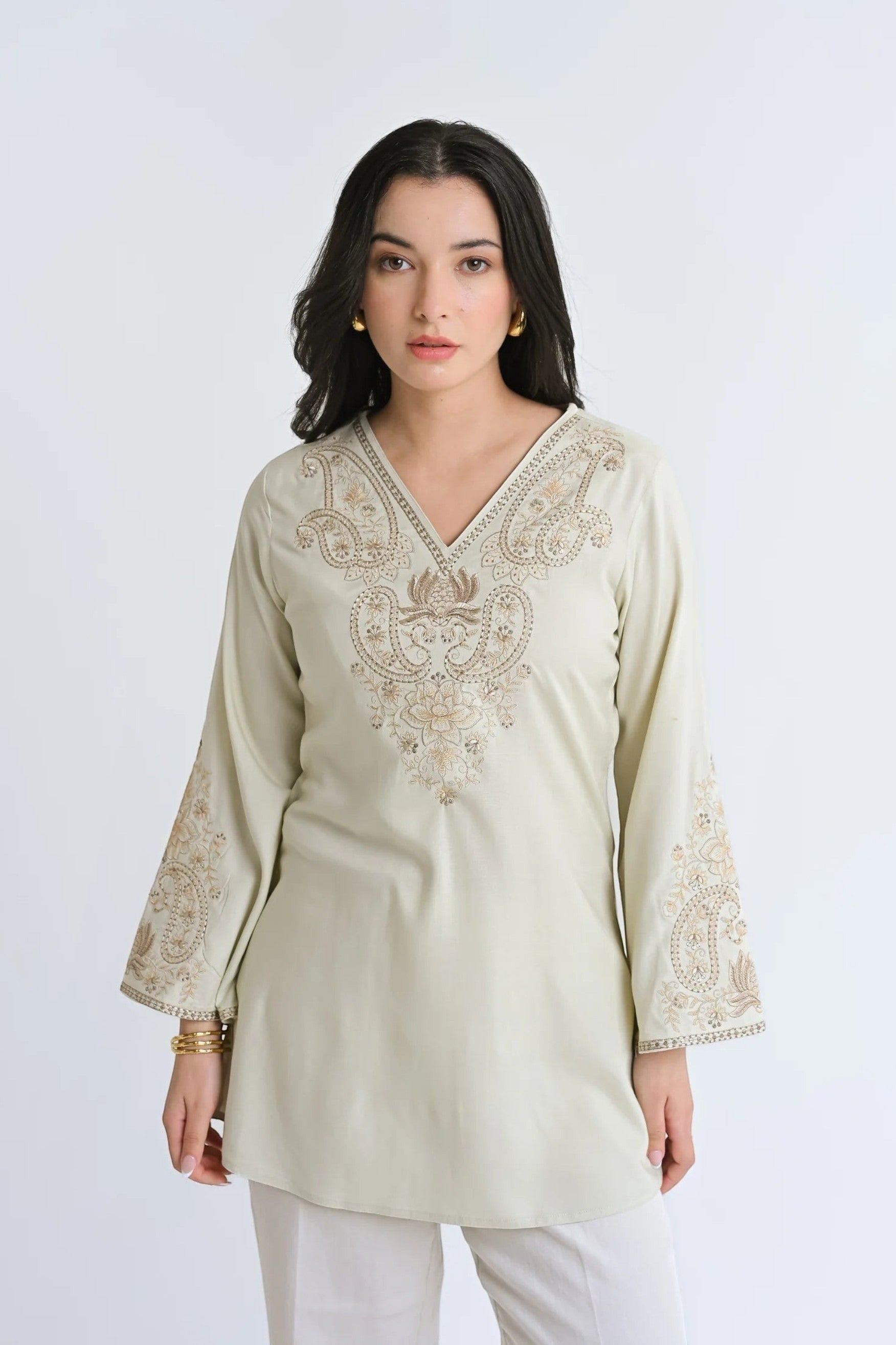 Model wearing an indigrey ivory Raya top with V-neck and intricate tonal corded stem fill embroidery on flared sleeves