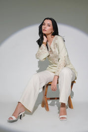 Model wearing an ivory indigrey Raya top with tonal corded stem fill embroidery, V-neck, and flared sleeves.