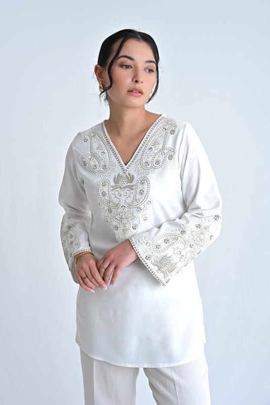 indigrey Raya white V-neck top featuring intricate corded stem fill embroidery and flared sleeves on a model.