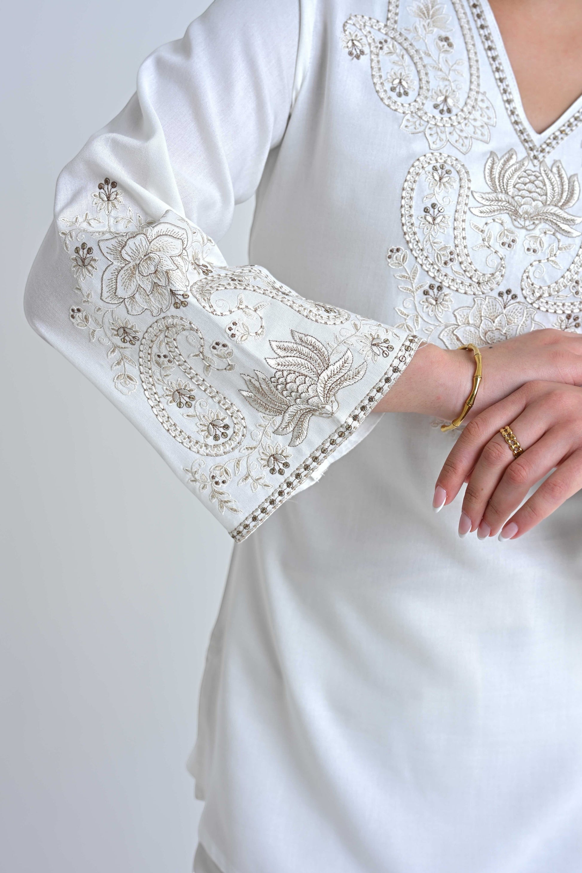 indigrey white Raya top with intricate corded stem fill embroidery, V-neck, and flared sleeves on a woman