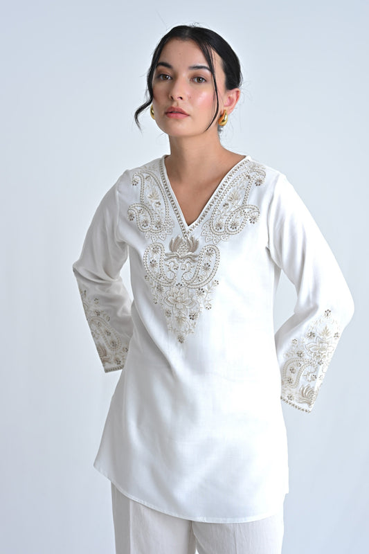 indigrey Raya white V-neck top featuring intricate corded stem fill embroidery on the neckline and flared sleeves.