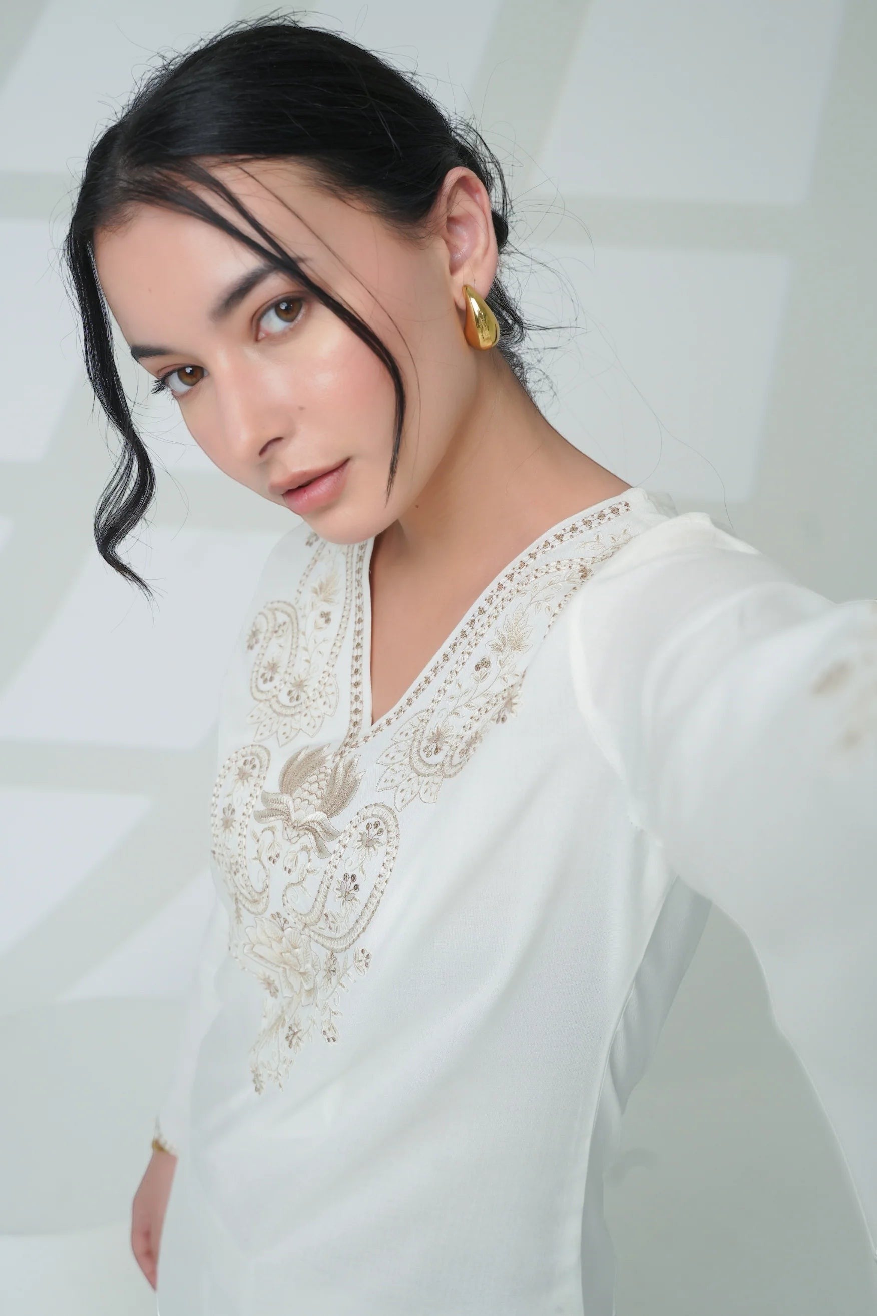 indigrey white Raya top featuring intricate corded stem fill embroidery, V-neck, and flared sleeves on a model.