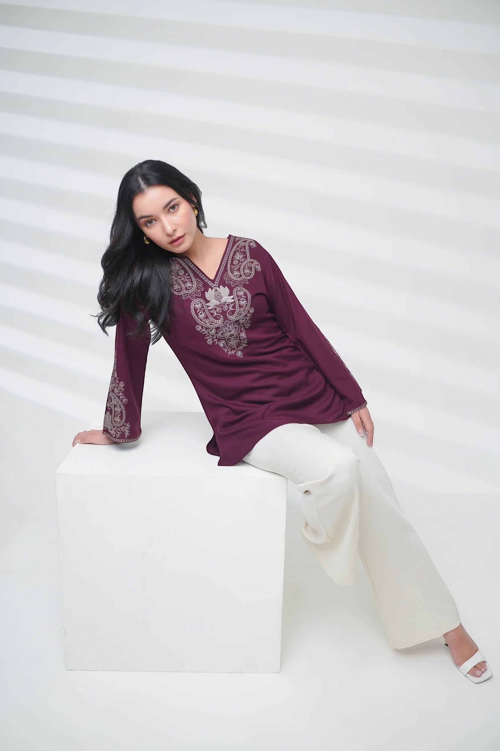 Model wearing an indigrey wine-colored Raya top with intricate corded stem fill embroidery and long sleeves.