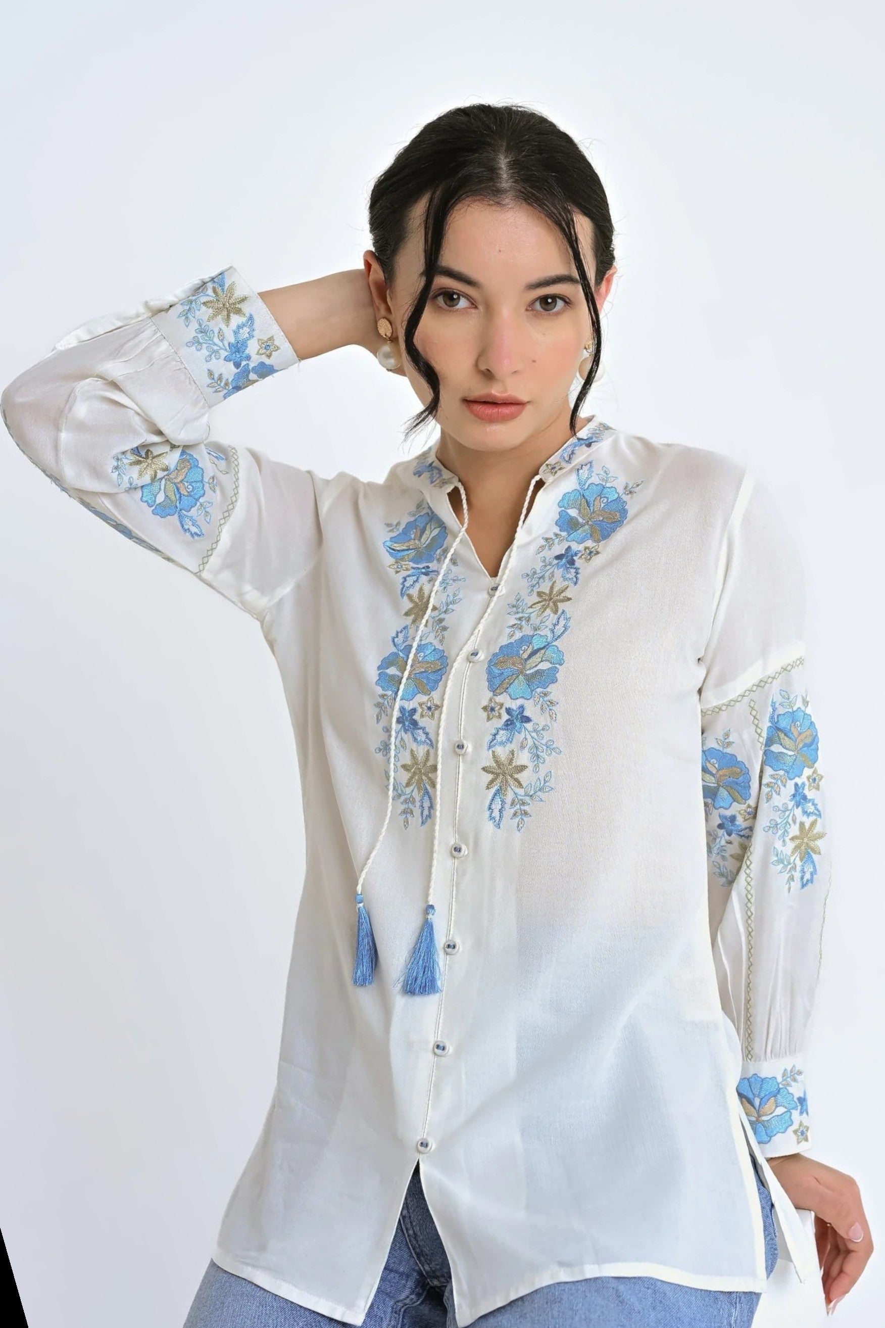 indigrey white shirt with blue floral Fly Brick stitch embroidery, tassel ties, and long sleeves on a woman