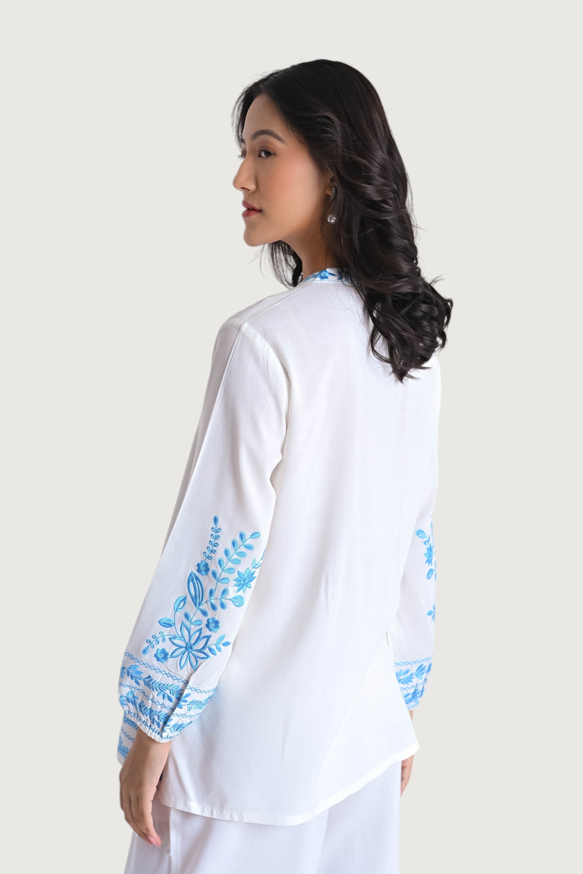 indigrey white viscose shirt with blue floral Tatami embroidery on sleeves and collar, worn by a woman