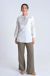 Model wearing an indigrey white top with intricate grey floral embroidery, long sleeves, and a relaxed straight fit.