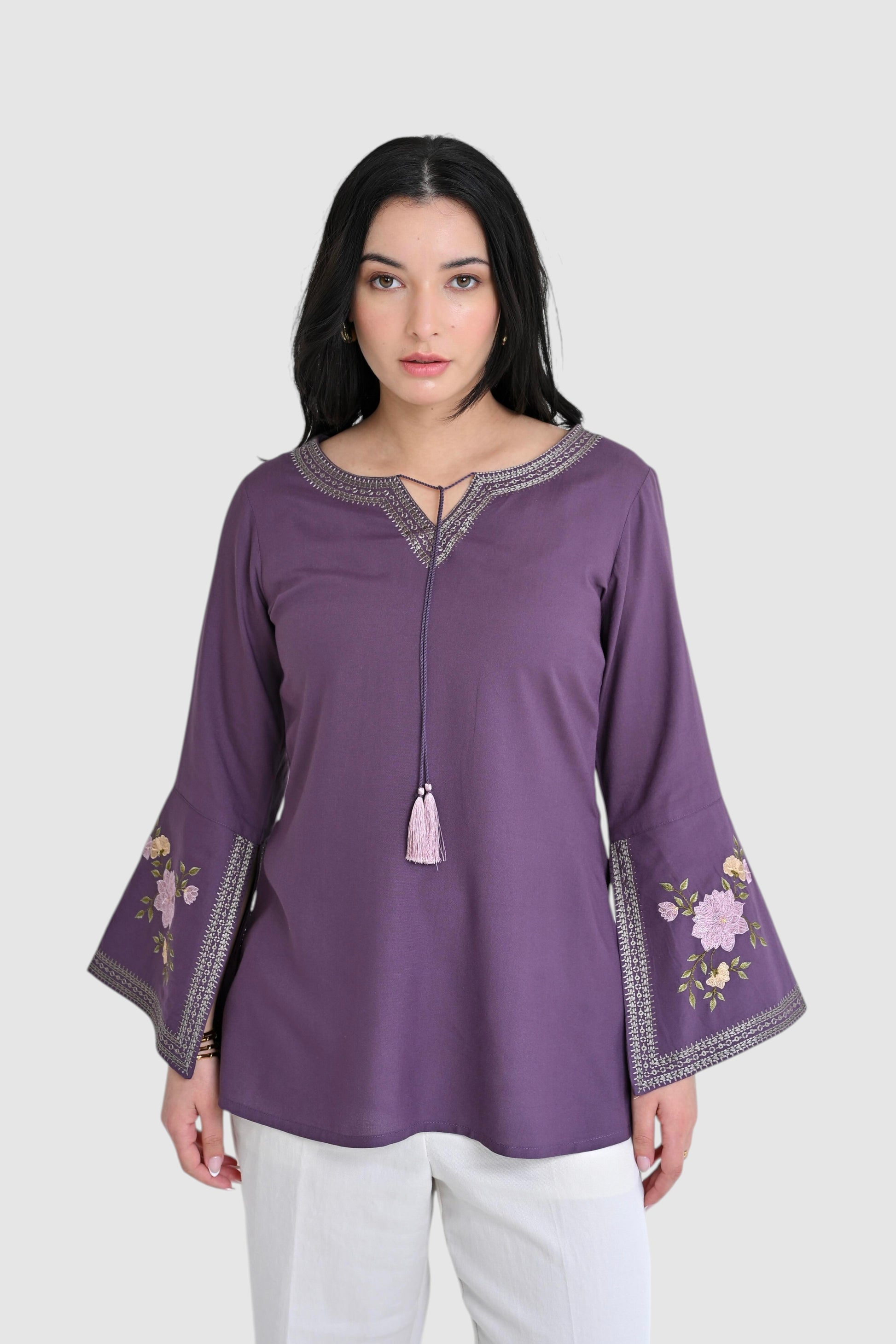 indigrey Zuri purple top with floral embroidery, bell sleeves, and tassel detail worn by a woman.
