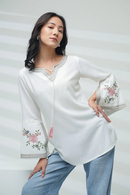 indigrey Zuri white top with floral Sketchfill Cord embroidery and flared bell sleeves worn by a woman